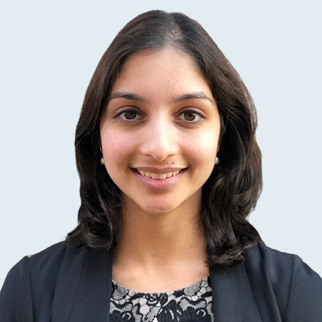 Heashot of Dr Neera Jain in a charcoal blazer and black and white lace blouse.